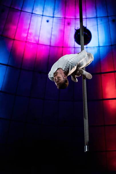 Starker Akrobat mit geschlossenen Augen auf metallischer Stange  - Foto, Bild