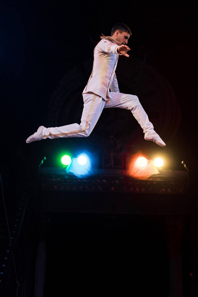 vue latérale d'acrobate aérien flexible volant dans l'arène du cirque
  - Photo, image