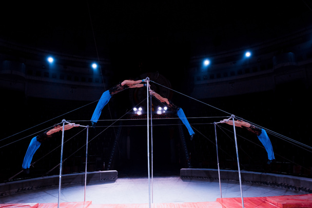 four gymnasts performing on horizontal bars in circus   - Photo, Image