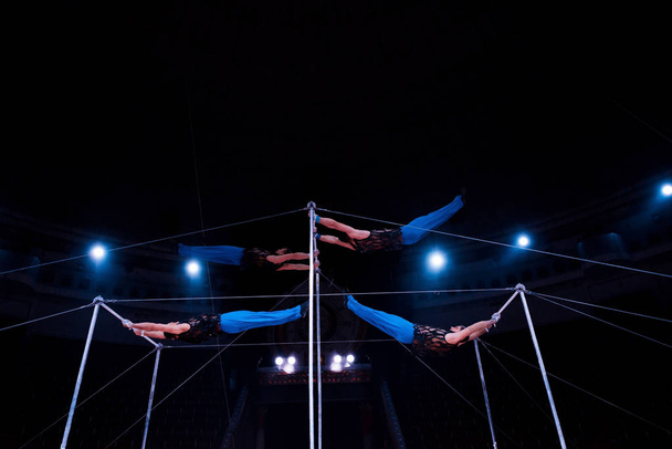 four acrobats performing on horizontal bars in circus   - Photo, Image
