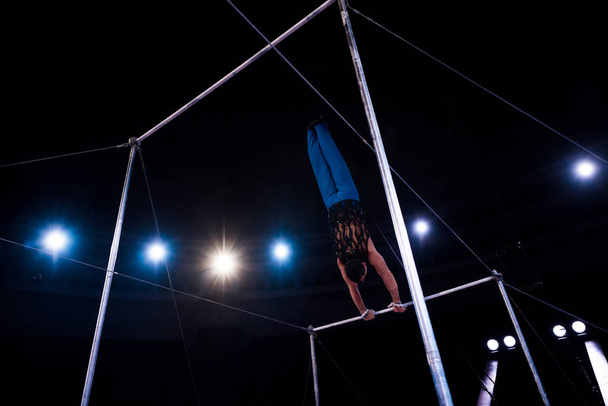 πίσω όψη γυμναστής εκτελεί σε οριζόντιες μπαρ στο τσίρκο   - Φωτογραφία, εικόνα