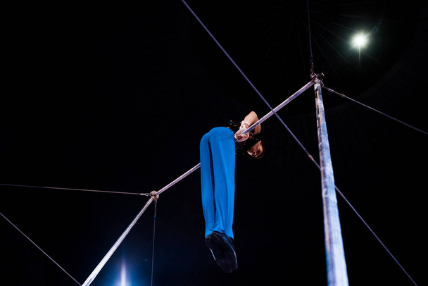 низький кут зору гнучкої гімнастки, що виступає на горизонтальних брусах на арені цирку
   - Фото, зображення