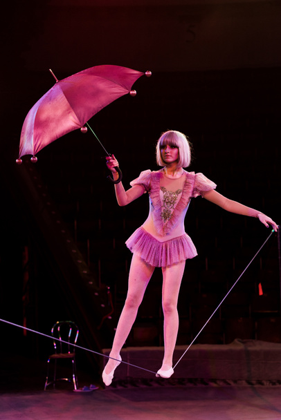 atrakcyjny akrobata w stroju trzymając parasol i stojąc na linie  - Zdjęcie, obraz