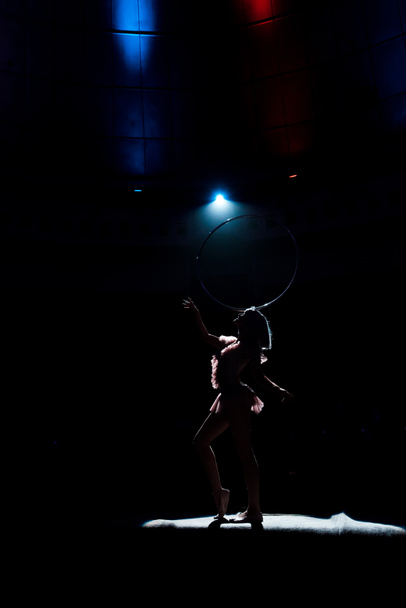 silhouette of aerial acrobat standing on rope with hula hoop  - Zdjęcie, obraz