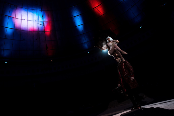 houkutteleva akrobaatti suorittaa istuessaan hattu mies sirkuksessa
  - Valokuva, kuva