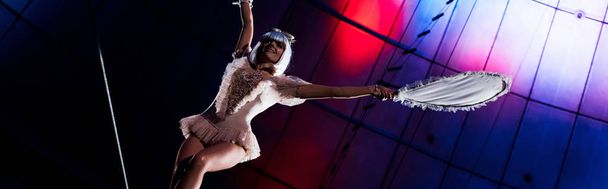 panoramic shot of attractive aerial acrobat holding racket while standing on rope  - Foto, immagini