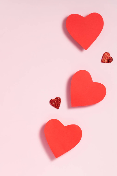 バレンタインデーのフレーム構成。パステルピンクの背景に赤い心。トップビュー、フラットレイアウト、コピースペース - 写真・画像