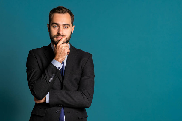 Serious thinking businessman looking around on blue background. Confused pensive face expressions. Handsome male model in corporate suit. - Foto, imagen