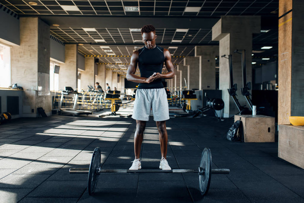 Мускулистый спортсмен в спортивной одежде готовится к упражнениям с штангой на тренировке в тренажерном зале. Тренировки в спортивном клубе, здоровый образ жизни
 - Фото, изображение