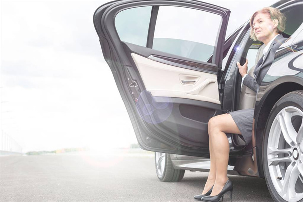Mature businesswoman disembarking car  - Fotoğraf, Görsel