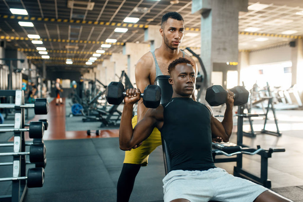 İki adam ağırlık kaldırarak egzersiz yapıyor, spor salonunda antrenman yapıyor. Spor kulübünde antrenman, sağlıklı yaşam tarzı, fitness - Fotoğraf, Görsel