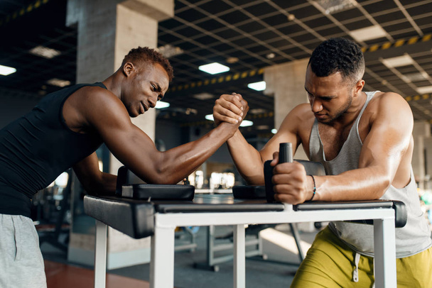 Dwóch mężczyzn walczących na rękach, trenujących zapasy na siłowni. Odpowiedni trening w klubie sportowym, zdrowy tryb życia, fitness - Zdjęcie, obraz