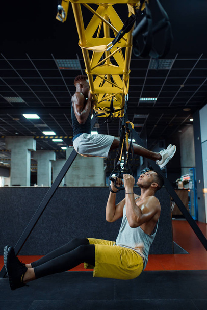 Мускулистый спортсмен в спортивной форме при растяжке тренажера на тренировке в тренажерном зале. Тренировки в спортивном клубе, здоровый образ жизни
 - Фото, изображение