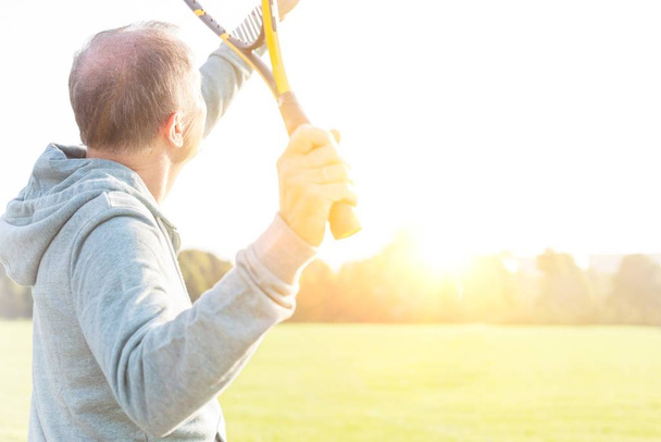 Активний старший чоловік грає в бадмінтон з тенісною ракеткою в парку
 - Фото, зображення