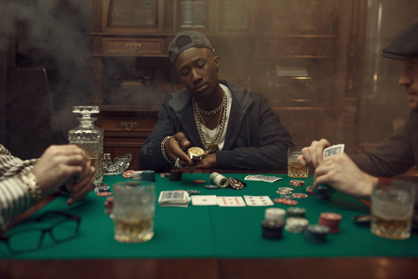 Pokerspieler macht eine Wette, Casino. Glücksspielsucht. Mann vergnügt sich in Spielothek, Spieltisch mit grünem Tuch - Foto, Bild