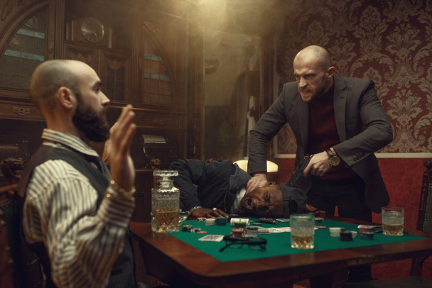 銃を持つポーカープレーヤー,カジノでの対戦相手と対決,リスク.チャンス中毒のゲーム。ギャンブルハウスにウイスキーと葉巻を持つ男 - 写真・画像
