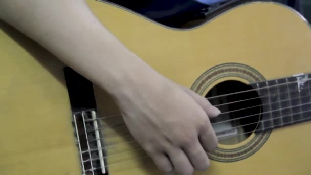 Młody chłopiec uczy się grać na gitarze, patrzeć z bliska na rękę. Gitarzysta edytować struny gitarowe. - Materiał filmowy, wideo