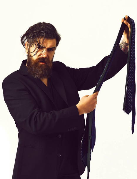 Brutal caucasian hipster in black suit holding ties - Photo, image