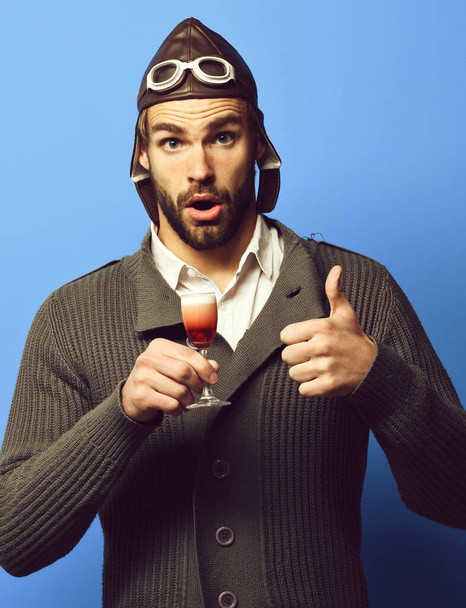 bearded pilot with cocktail in glass on blue studio background - Foto, immagini