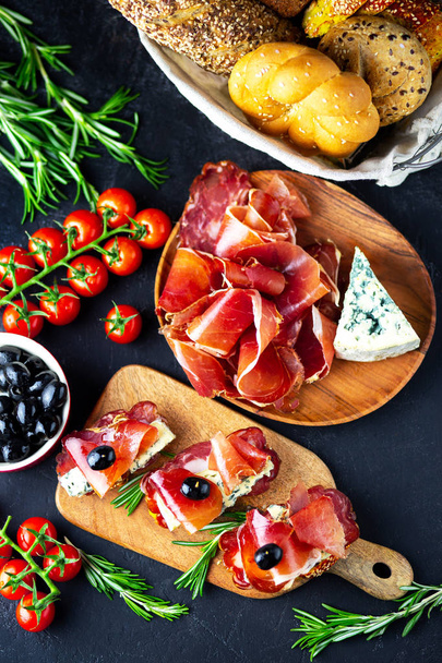 Table appetizers with Italian antipasto appetizers. Bruschetta or authentic traditional spanish tapas set, cheese board. Wine snack on a wooden board. Cheese, jamon, prosciutto and cherry tomatoes. - Photo, image