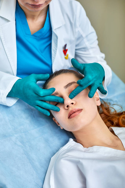鼻の上に石膏を持つ女性医師試験の患者の顔の整形手術後 - 写真・画像