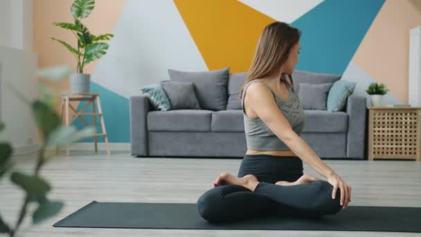 Attractive female adult working out in lotus position at home sitting on yoga mat - Footage, Video
