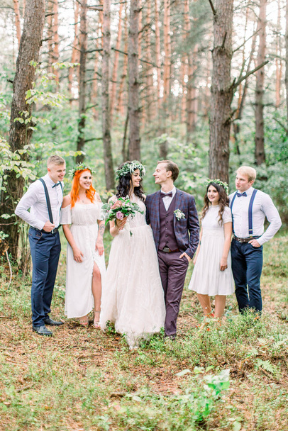 Bräutigam mit Braut und ihren Freunden. Rustikale Herbsthochzeit im Kiefernwald. fröhliche Freunde. Hochzeitstag nach der Trauung - Foto, Bild