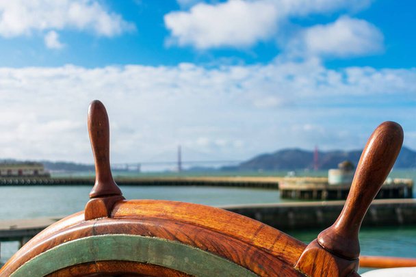 Fecha. Volante de navio com cais embaçado, Golden Gate Bridge e fundo de paisagem marinha no horizonte nublado
 - Foto, Imagem