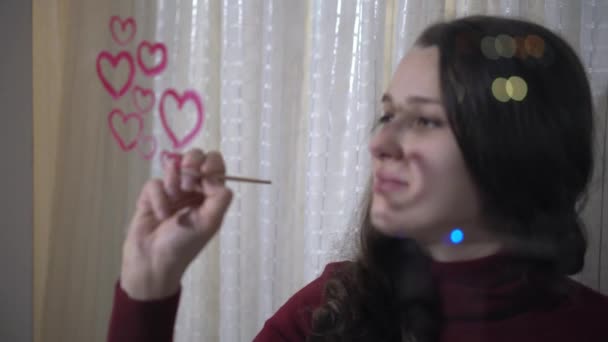 Beautiful girl paints a heart on glass - Video, Çekim