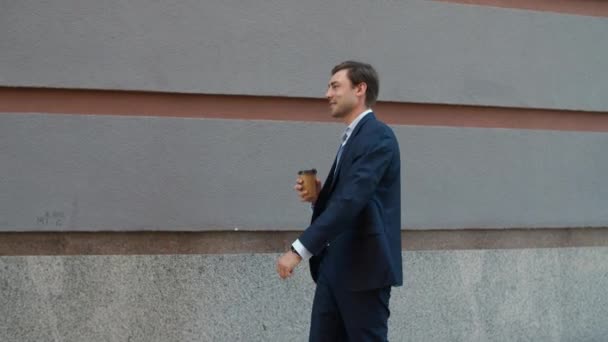 Smiling man drinking coffee at street. Businessman walking to work with coffee - Felvétel, videó