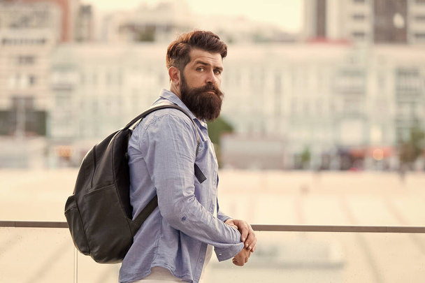 Backpack for travelling and city life. Hipster wearing backpack in casual style on urban outdoor. Bearded man travelling with backpack on summer vacation. Taking backpack in backpacking trip - Fotó, kép