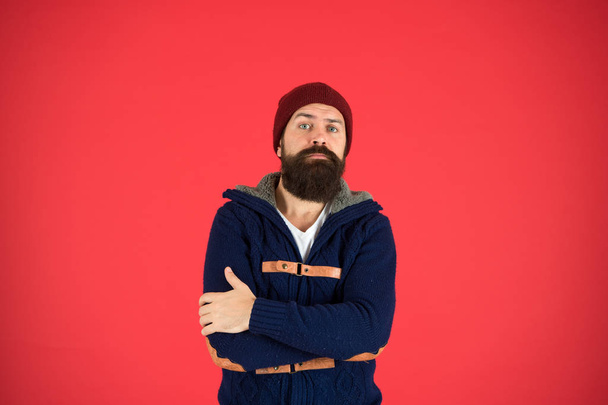 Warm and comfortable. Fashion menswear shop. Masculine clothes concept. Think and decide. Winter menswear. Man bearded warm jumper and hat red background. Winter season menswear. Personal stylist - Fotó, kép