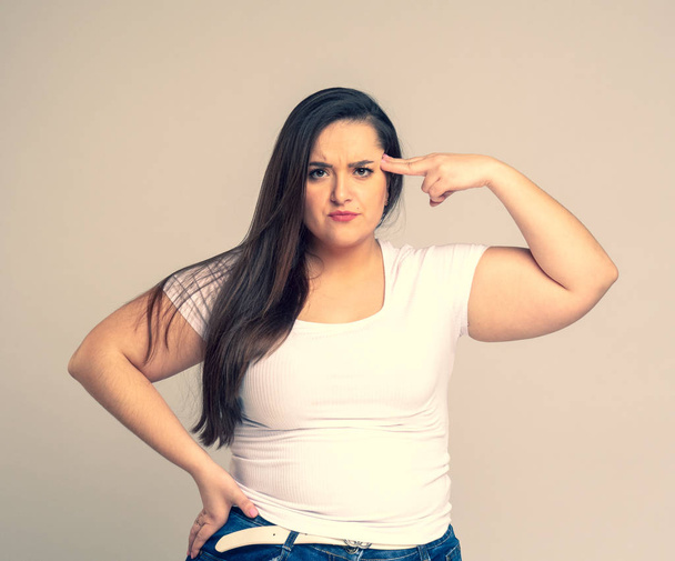 Portrait of serious plus size woman standing saluting with hand near head - Photo, Image