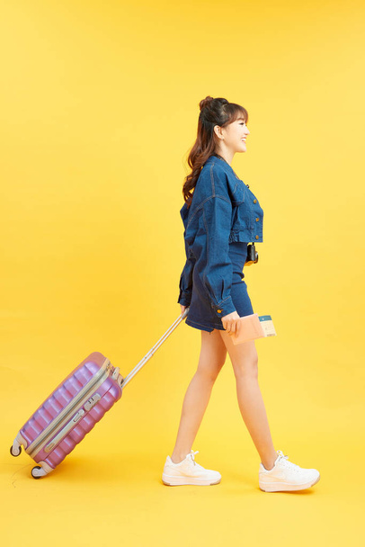 travel, tourism and people concept - smiling young woman with airplane ticket and bag - 写真・画像