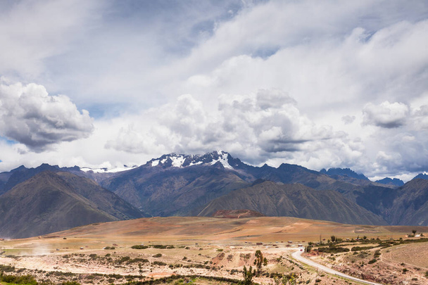 Cordillera en las nubes, en el terreno desierto en primer plano
 - Foto, imagen