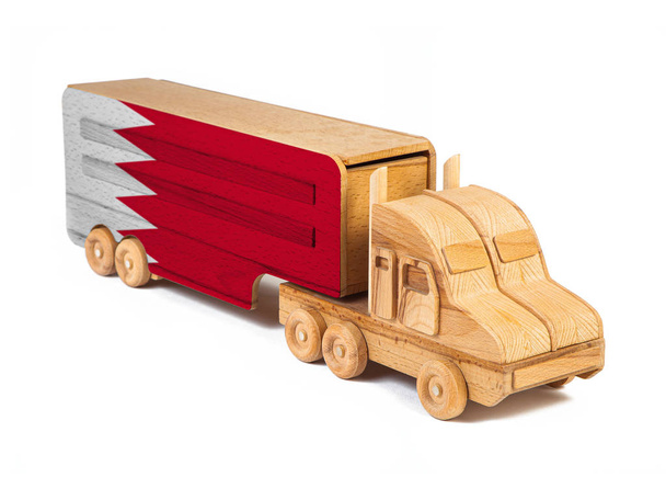 Κοντινό πλάνο ενός ξύλινου φορτηγού παιχνιδιών με γραπτή εθνική σημαία του Μπαχρέιν. Η έννοια της εξαγωγής-εισαγωγής, μεταφοράς, εθνικής παράδοσης αγαθών  - Φωτογραφία, εικόνα
