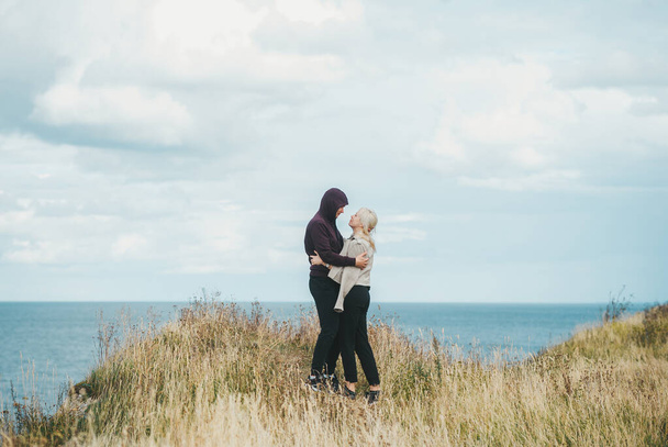 バルト海の岩場の海岸の端に抱擁するカップルのロマンチックな景色. - 写真・画像