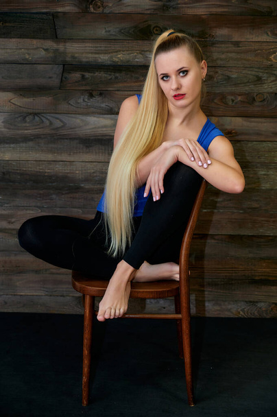 Art concept of a stylish model portrait. Portrait of a slender woman with long beautiful hair and excellent make-up on a creative background of wood in the loft style. - Foto, Imagen