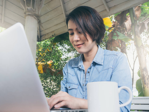 Όμορφη ευτυχισμένη Ασιάτισσα γυναίκα χρησιμοποιώντας φορητό υπολογιστή στο καφέ. - Φωτογραφία, εικόνα