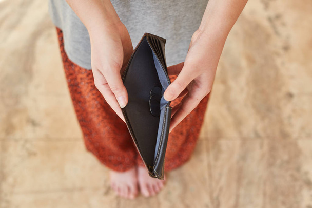 Dívka drží v rukou prázdnou peněženku. Konkurzní koncept. - Fotografie, Obrázek