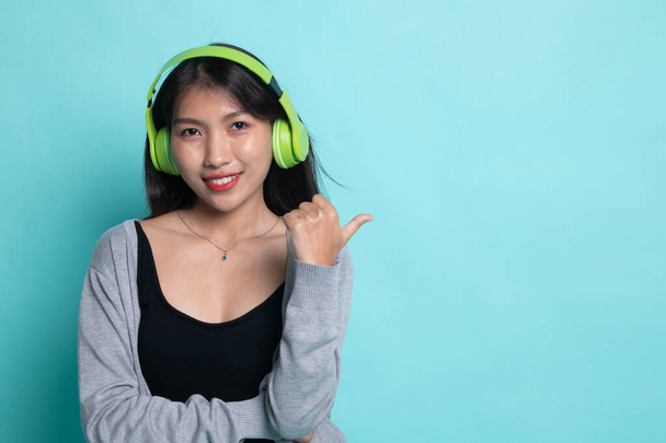 Pretty asian girl listening music with her headphones point to c - Valokuva, kuva
