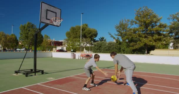 Vader met zoon basketbal spelend op het buitenveld. - Video
