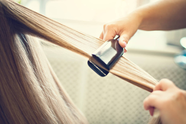 The hairdresser dries and combs a long fair hair. Hairdressing salon. - Fotografie, Obrázek