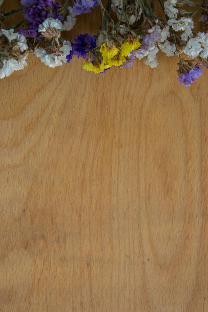 mehrfarbige getrocknete Blumen auf hölzernem Hintergrund, farbenfrohe Limoniumstatikpflanze mit Kopierraum, Platz für Text - Foto, Bild