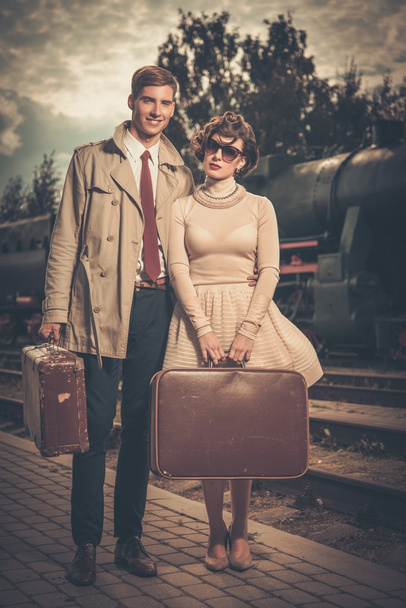 Vintage style couple with suitcases on train station - Fotó, kép