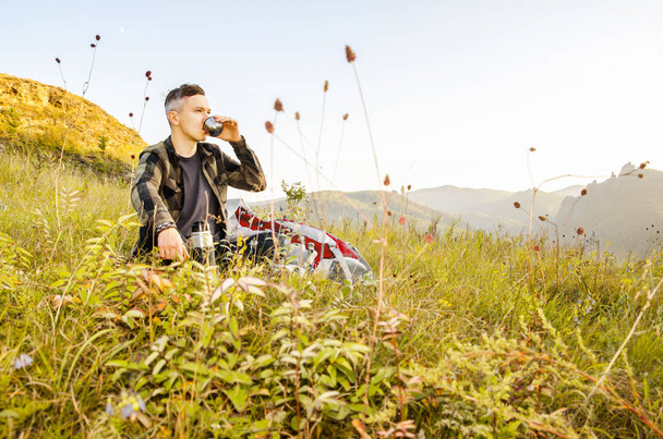 Hipster young man with backpack enjoying sunset on peak mountain. - Fotó, kép