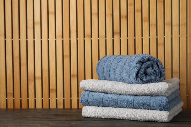 gefaltete Handtücher auf Holztisch vor Bambus-Hintergrund, Raum f - Foto, Bild