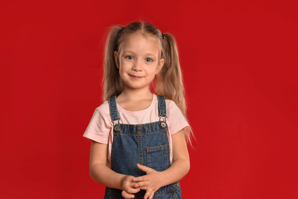 Portrait of cute little girl on red background - Foto, Imagem