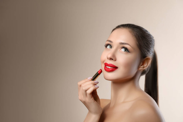 Beautiful woman with red lipstick on beige background, space for text - Фото, зображення