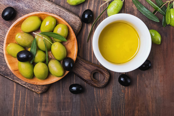 Olives and extra virgin olive oil in a bowl on wooden table - Foto, Imagen